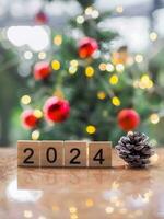 en bois bloquer nombre 2024 et pommes de pin avec Noël lumière bokeh Contexte. joyeux Noël et content Nouveau année 2024 photo