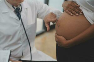 femelle médecin est vérification Enceinte femme avec stéthoscope. concept soins pour Enceinte femme photo