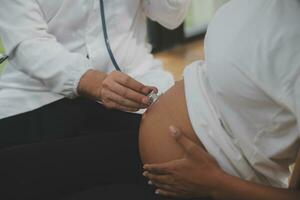 femelle médecin est vérification Enceinte femme avec stéthoscope. concept soins pour Enceinte femme photo