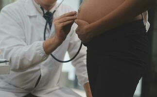 femelle médecin est vérification Enceinte femme avec stéthoscope. concept soins pour Enceinte femme photo