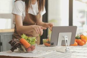 délicieux fruit et des légumes sur une table et femme cuisson. femme au foyer est Coupe vert concombres sur une en bois planche pour fabrication Frais salade dans le cuisine. photo