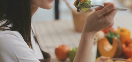 délicieux fruit et des légumes sur une table et femme cuisson. femme au foyer est Coupe vert concombres sur une en bois planche pour fabrication Frais salade dans le cuisine. photo