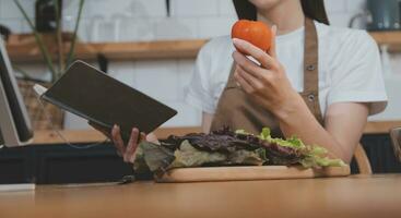 délicieux fruit et des légumes sur une table et femme cuisson. femme au foyer est Coupe vert concombres sur une en bois planche pour fabrication Frais salade dans le cuisine. photo