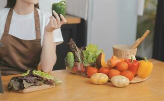 délicieux fruit et des légumes sur une table et femme cuisson. femme au foyer est Coupe vert concombres sur une en bois planche pour fabrication Frais salade dans le cuisine. photo