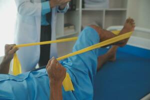 Masculin patient en utilisant élastique bande tandis que Faire physique des exercices pour jambe muscles à moderne clinique, réhabilitation centre ou hôpital. proche en haut de homme pied. physiothérapie concept photo