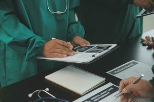 multiracial équipe de médecins discuter une patient permanent groupé dans le foyer à la recherche à une tablette ordinateur, proche en haut vue photo