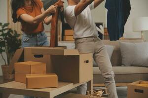 magnifique Jeune couple dans l'amour ayant amusement déballage des choses de papier carton des boites tandis que en mouvement dans ensemble dans leur Nouveau appartement photo