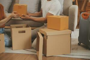 magnifique Jeune couple dans l'amour ayant amusement déballage des choses de papier carton des boites tandis que en mouvement dans ensemble dans leur Nouveau appartement photo