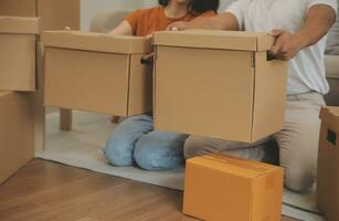 magnifique Jeune couple dans l'amour ayant amusement déballage des choses de papier carton des boites tandis que en mouvement dans ensemble dans leur Nouveau appartement photo