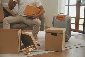 magnifique Jeune couple dans l'amour ayant amusement déballage des choses de papier carton des boites tandis que en mouvement dans ensemble dans leur Nouveau appartement photo