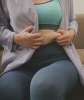 une femme spectacles un gonflé épais ventre, le concept de excès poids et poids perte photo
