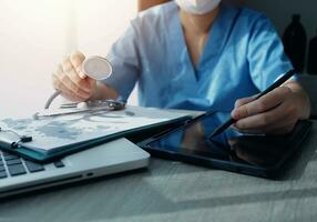 médecins travail sur portable ordinateur, l'écriture ordonnance presse-papiers avec record information papier Dossiers sur bureau dans hôpital ou clinique, soins de santé et médical concept. concentrer sur stéthoscope photo