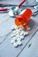 pilules médicales de couleur blanche se déversant sur une table en bois photo