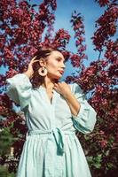 une jeune fille se tient dans le parc sous un pommier en fleurs photo