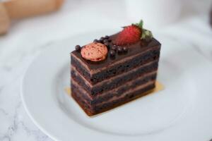 pièce de Chocolat gâteau avec des fraises et macarons sur blanc assiette photo