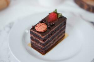 pièce de Chocolat gâteau avec des fraises et macarons sur blanc assiette photo