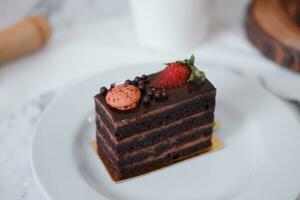 pièce de Chocolat gâteau avec des fraises et macarons sur blanc assiette photo