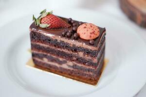 pièce de Chocolat gâteau avec des fraises et macarons sur blanc assiette photo