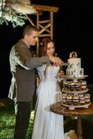 les jeunes mariés coupent et goûtent joyeusement le gâteau de mariage photo