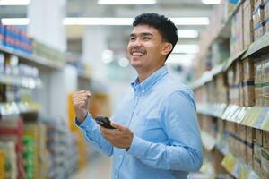 content asiatique homme dans décontractée bleu chemise dans le supermarché. concepts détail. petit entreprises et supermarchés. photo