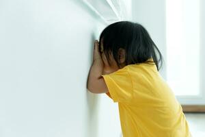 peu asiatique les enfants enfant fille couvrant le sien yeux avec mains, en jouant cacher et chercher permanent suivant une mur loger, adorable enfant ayant amusement dans le maison. content famille avoir amusement avec enfants, activité photo