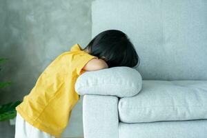 peu asiatique les enfants enfant en jouant cacher et chercher permanent derrière le canapé, adorable enfant ayant amusement dans le maison. content famille avoir amusement avec enfants, activité, apprentissage, activité, jeu, méditation photo