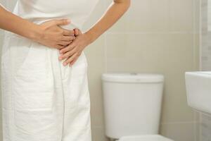 constipation et diarrhée dans la salle de bain. blesser la femme toucher le ventre mal de ventre douloureux. problème d'inflammation du côlon, aliments toxiques, douleurs abdominales, abdomen, toilettes constipées, maux de ventre, hygiène photo