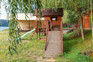 aire de jeux pour enfants en bois moderne vide située sur une cour verte dans un parc public en été. terrain de jouets amusant pour les enfants. activités d'exercice urbain pour enfant à l'extérieur. concept d'enfance de quartier. photo