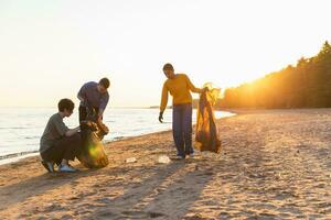 Terre journée. bénévoles militants recueille des ordures nettoyage de plage côtier zone. femme et mans met Plastique poubelle dans des ordures sac sur océan rive. environnement préservation côtier zone nettoyage. photo