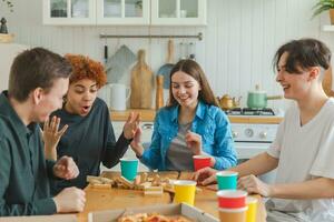 Accueil faire la fête. copains dépenses temps ensemble en jouant dans planche Jeu crash en bois la tour à maison. content diverse groupe ayant amusement ensemble intérieur. mixte course Jeune copains meilleur copains profiter fin de semaine. photo