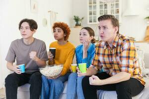 groupe de copains en train de regarder sport rencontre football Football Jeu sur la télé. content Football Ventilateurs célébrer la victoire à maison. relation amicale des sports divertissement concept. diverse copains ayant amusement ensemble à maison. photo