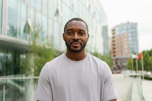 content africain américain homme souriant Extérieur. portrait de Jeune content homme sur rue dans ville. de bonne humeur joyeux Beau la personne gars à la recherche à caméra. liberté bonheur insouciant content gens concept. photo