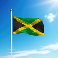 agitant drapeau de Jamaïque sur mât avec ciel Contexte. photo