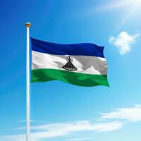 agitant drapeau de Lesotho sur mât avec ciel Contexte. photo