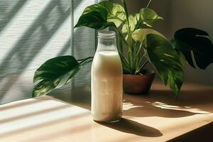 une bouteille de Lait est assis sur une table suivant à une plante photo