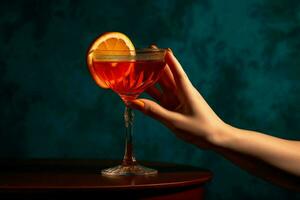 une main en portant une rouge cocktail verre avec une tranche photo