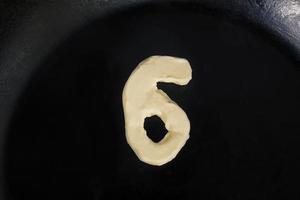 beurre en forme de numéro 6 sur une poêle chaude - vue de dessus en gros plan photo