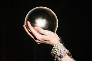 les mains de la diseuse de bonne aventure sur un globe de verre sur fond noir. photo