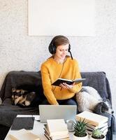 jeune femme souriante dans des écouteurs noirs étudiant en ligne à l'aide d'un ordinateur portable photo