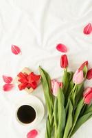 tulipes roses, tasse à café et vue de dessus de cadeau sur lit blanc photo