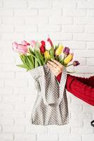 main de femme tenant un sac en tissu à pois gris avec des tulipes colorées photo