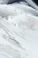 deux gens sont randonnée en haut une Montagne avec neige couvert montagnes photo