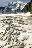 deux gens sont randonnée en haut une Montagne avec neige couvert montagnes photo