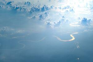 aérien vue de avion fenêtre de blanc bouffi des nuages sur brillant ensoleillé journée ang embrasé rivière. photo