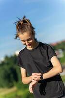 adolescent fille dans noir vêtements vérification sa aptitude regarder après une entraînement. photo