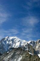 deux gens sont randonnée en haut une Montagne avec neige couvert montagnes photo