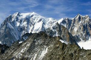 deux gens sont randonnée en haut une Montagne avec neige couvert montagnes photo