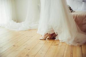 une mariée en robe de mariée et chaussures sur plancher en bois photo