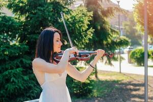 femme artiste avec foncé cheveux dans une robe pièces une en bois concert électrique violon photo