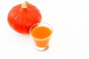 une verre de Orange jus avec une citrouille sur une lumière Contexte photo